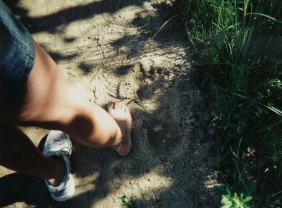 Crystal Olson, 5-feet 6-inches tall with an 8-inch foot, stands alongside a 15-inch Bigfoot track discovered near Bena, Minnesota on June 7, 2006.jpg